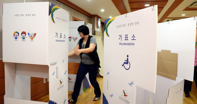 An election official installs voting booths at a polling station in Seoul (Ahn Hoon/The Korea Herald)