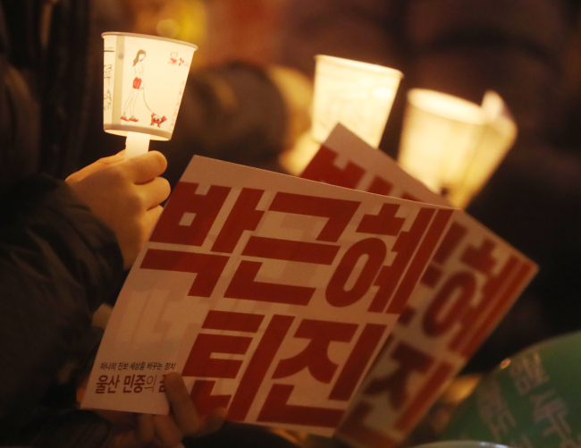 Protestors hold candles and signs that have slogans calling for the immediate ouster of President Park Geun-hye during a rally in Seoul last year (Yonhap)