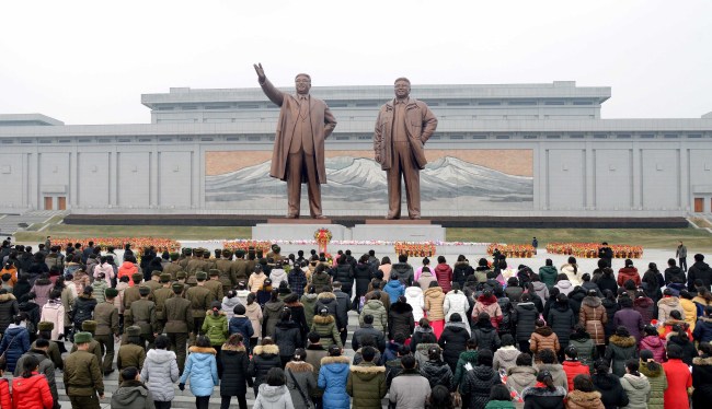 North Koreans gather around the statues of Kim Il-sung and Kim Jong-un to offer their regular floral tributes (Yonhap)