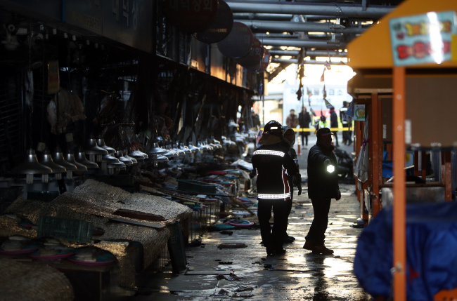 Firefighters walk around the Yeosu fish market to check on the extent of damage caused by fire (Yonhap)