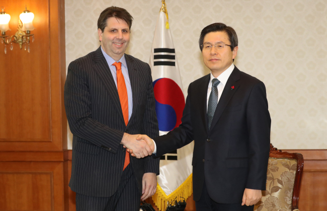 Acting President and Prime Minister Hwang Kyo-ahn (right) shakes with US ambassador Mark Lippert (Yonhap)