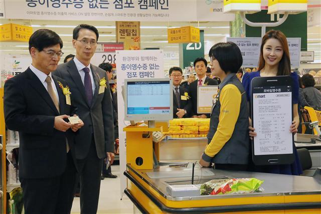 지난 19일 서울 성동구 이마트 성수점에서 ‘종이영수증 없는 점포 캠페인’이 펼쳐진 가운데 조경규 환경부 장관(좌측)과 이갑수 이마트 대표이사(좌측에서 두번째)가  모바일영수증을 시연해 보고 있다. 이마트, 종이영수증 없는 점포 만든다.