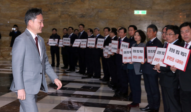 Rep. Pyo Chang-won of the Democratic Party walks into a general meeting at the National Assembly building where Saenuri Party lawmakers are holding signs demanding his resignation (Yonhap)