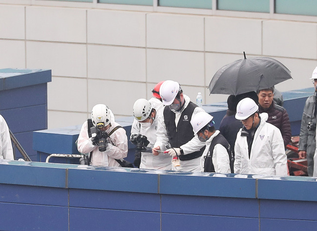 Police officers and fire authorities examine a fire site in Dongtan, Geonggi Province, on Saturday (Yonhap)