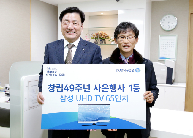 DGB대구은행은 지난해 창립 49주년을 기념해 진행한 대고객 사은행사 당첨자를 발표했다고 12일 밝혔다. 사진은 지난 10일 DGB대구은행 성명지점에서 성무용 부행장(왼쪽)이 1등 당첨고객 김희철씨에게 1등 상품을 전달하는 모습. [사진제공=DGB대구은행]