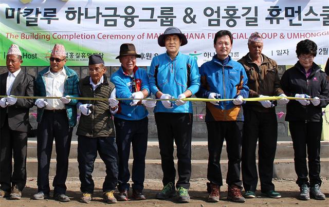 김정태 하나금융그룹 회장(왼쪽 다섯 번째)과 산악인 엄홍길 대장(왼쪽 네 번째) 등 관계자들과 마을 주민들이 휴먼스쿨 앞에서 준공 기념 테이프 커팅식을 갖고 기념촬영을 하고 있다.  [사진제공=하나금융그룹]