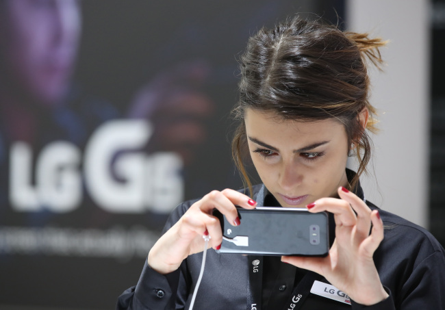 A model looks at LG Electronics' new G6 smartphone at the Mobile World Congress in Barcelona on Monday. (Yonhap)