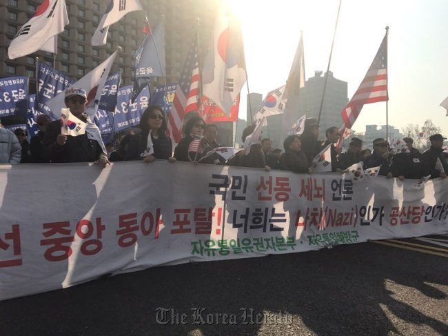 Pro-Park protestors hold a placard likening major newspapers to the Nazi and communists during a rally around Seoul Plaza on Saturday. (Bak Se-hwan/The Korea Herald)