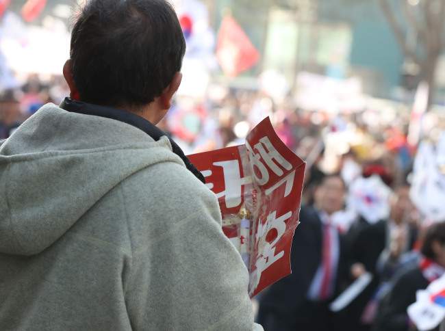 A pro-Park protester holds a sign calling for the invalidation of the impeachment during a rally in central Seoul on Saturday. (Yonhap)