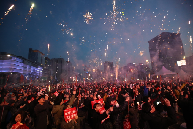 South Koreans let off fireworks in celebration of the impeachment of former President Park Geun-hye during a rally in central Seoul on Saturday. (Yonhap)