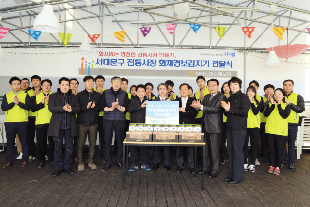 농협손해보험 이윤배 대표(왼쪽 다섯 번째)와 봉사단이 전통시장인 영천시장, 포방터 시장, 인왕시장 상인회장에게 화재경보감지기를 전달한 후 기념촬영 하고 있다.
