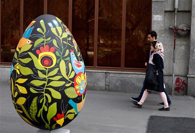 <YONHAP PHOTO-0384> epa05852487 An Iranian couple walk passes next to a large decorated egg which is a symbol of Nowruz, the Persian New Year, as displayed by municipality in a street of Tehran, Iran, 16 March 2017. The Persian New Year, starting on 20 March, also marks the beginning of spring. The Persian New Year which has been celebrated for at least 3,000 years is the most revered celebration in the greater Persian world, which includes the countries of Iran, Afghanistan, Azerbaijan, Turkey, portions of western China, and northern Iraq. EPA/ABEDIN TAHERKENAREH/2017-03-17 01:47:56/ <저작권자 ⓒ 1980-2017 ㈜연합뉴스. 무단 전재 재배포 금지.>