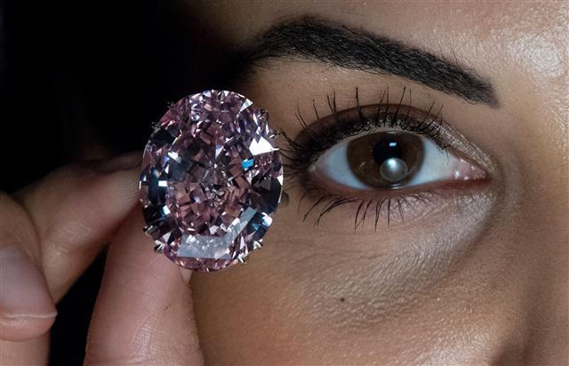 <YONHAP PHOTO-4810> A model poses with a 59.60-carat oval mixed-cut pink diamond, known as "The Pink Star", during a photocall at Sotheby's auction house in London on March 20, 2017, to promote its forthcoming auction. The diamond, with an estimated value of 48.5 million GBP (60 million euros; 60 million USD), is said to be the largest Internally Flawless Fancy Vivid Pink diamond that the Gemological Institute of America (GIA) has ever graded, and is set to be auctioned in Hong Kong on April 4, 2017. / AFP PHOTO / Justin TALLIS/2017-03-20 22:11:06/ <저작권자 ⓒ 1980-2017 ㈜연합뉴스. 무단 전재 재배포 금지.>