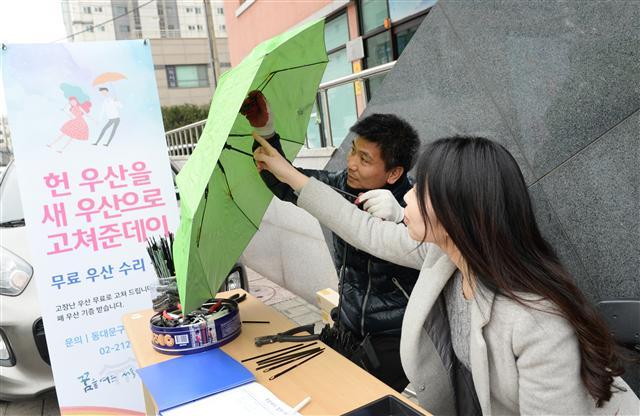 지난 20일 동대문구 용신동주민센터 앞에서 한 여성이 망가진 우산을 수리하고 있다. 과거에는 우산을 수리해 재사용하는 경우가 많았으나 최근에는 수리하는 모습은 찾아보기 힘든 상황이다.서울 동대문구(구청장 유덕열)는 지난 20일부터 ‘헌우산 고쳐준데이’를 관내 14개 동주민센터를 순회하며 헌 우산을 새 우산으로 고쳐주는 무료 수리사업을 실시하고 있다.  [사진제공=동대문구]