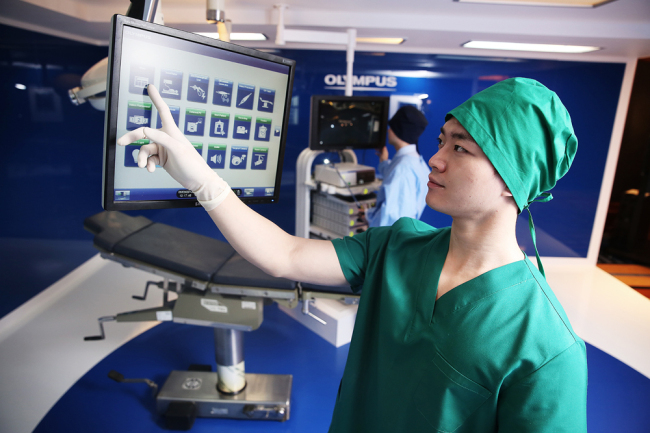 A model uses the smart touch panel from Olympus Korea’s newly-launched surgical system integration solution Endoalpha during a demonstration in Seoul, Tuesday. (Olympus Korea)