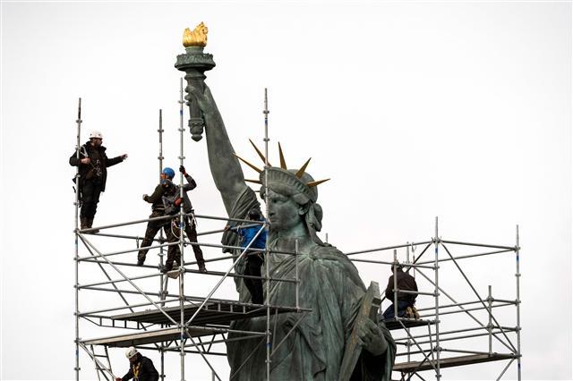 <YONHAP PHOTO-0294> Workers stand on scaffolding erected around the Statue of Liberty replica by French sculptor Auguste Bartholdi (1834-1904) for renovation works on the Ile aux Cygnes in Paris on March 21, 2017. / AFP PHOTO / Lionel BONAVENTURE/2017-03-22 01:00:03/ <저작권자 ⓒ 1980-2017 ㈜연합뉴스. 무단 전재 재배포 금지.>