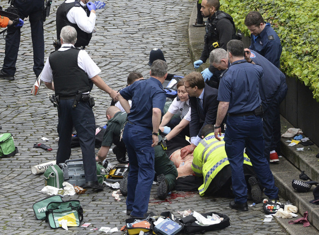 <YONHAP PHOTO-1407> Conservative Member of Parliament Tobias Ellwood, centre, helps emergency services attend to an injured person outside the Houses of Parliament, London, Wednesday, March 22, 2017. London police say they are treating a gun and knife incident at Britain's Parliament "as a terrorist incident until we know otherwise." The Metropolitan Police says in a statement that the incident is ongoing. It is urging people to stay away from the area. Officials say a man with a knife attacked a police officer at Parliament and was shot by officers. Nearby, witnesses say a vehicle struck several people on the Westminster Bridge. (Stefan Rousseau/PA via AP)./2017-03-23 02:54:04/ <저작권자 ⓒ 1980-2017 ㈜연합뉴스. 무단 전재 재배포 금지.>
<YONHAP PHOTO-1407> Conservative Member of Parliament Tobias Ellwood, centre, helps emergency services attend to an injured person outside the Houses of Parliament, London, Wednesday, March 22, 2017. London police say they are treating a gun and knife incident at Britain's Parliament "as a terrorist incident until we know otherwise." The Metropolitan Police says in a statement that the incident is ongoing. It is urging people to stay away from the area. Officials say a man with a knife attacked a police officer at Parliament and was shot by officers. Nearby, witnesses say a vehicle struck several people on the Westminster Bridge. (Stefan Rousseau/PA via AP)./2017-03-23 02:54:04/ <저작권자 ⓒ 1980-2017 ㈜연합뉴스. 무단 전재 재배포 금지.>