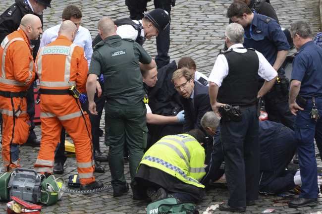 <YONHAP PHOTO-0930> Conservative Member of Parliament Tobias Ellwood, centre, helps emergency services attend to an injured person outside the Houses of Parliament, London, Wednesday, March 22, 2017. London police say they are treating a gun and knife incident at Britain's Parliament "as a terrorist incident until we know otherwise." The Metropolitan Police says in a statement that the incident is ongoing. It is urging people to stay away from the area. Officials say a man with a knife attacked a police officer at Parliament and was shot by officers. Nearby, witnesses say a vehicle struck several people on the Westminster Bridge. (Stefan Rousseau/PA via AP)./2017-03-23 01:49:14/ <저작권자 ⓒ 1980-2017 ㈜연합뉴스. 무단 전재 재배포 금지.>
<YONHAP PHOTO-0930> Conservative Member of Parliament Tobias Ellwood, centre, helps emergency services attend to an injured person outside the Houses of Parliament, London, Wednesday, March 22, 2017. London police say they are treating a gun and knife incident at Britain's Parliament "as a terrorist incident until we know otherwise." The Metropolitan Police says in a statement that the incident is ongoing. It is urging people to stay away from the area. Officials say a man with a knife attacked a police officer at Parliament and was shot by officers. Nearby, witnesses say a vehicle struck several people on the Westminster Bridge. (Stefan Rousseau/PA via AP)./2017-03-23 01:49:14/ <저작권자 ⓒ 1980-2017 ㈜연합뉴스. 무단 전재 재배포 금지.>