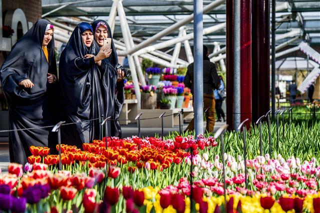 epa05865482 Tourists wearing chadors take pictures among flowers at the Keukenhof garden in Lisse, Netherlands, 23 March 2017. This year's theme of the tourist attraction floral park is the Dutch Design. EPA/ROBIN UTRECHT
