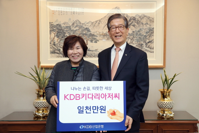 Korea Development Bank’s Lee Dong-geol (right) delivers a donation of 10 million won to Kang Myeong-hee, the head of the “Daddy-long-legs Classroom” program. (KDB)