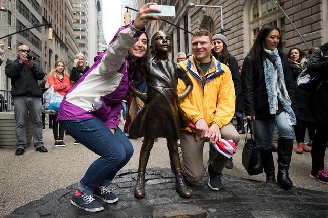 <YONHAP PHOTO-0898> NEW YORK, NY - MARCH 27: Visitors pose for photos with the 'Fearless Girl' statue, March 27, 2017 in New York City. New York City Mayor Bill De Blasio announced that the popular statue of a young girl staring down the famous Wall Street 'Charing Bull' will stay in place until February 2018. Drew Angerer/Getty Images/AFP == FOR NEWSPAPERS, INTERNET, TELCOS & TELEVISION USE ONLY ==/2017-03-28 05:16:08/ <저작권자 ⓒ 1980-2017 ㈜연합뉴스. 무단 전재 재배포 금지.>