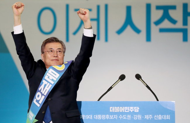 Moon Jae-in (left) raises his hands during the Democratic Party of Korea’s primary race held Monday at Gocheok Sky Dome in western Seoul. (Yonhap)