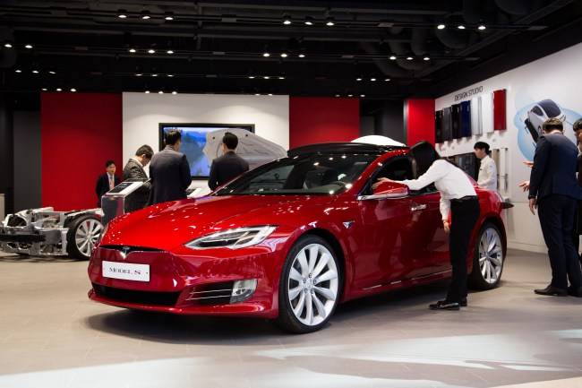 An employee assists a customer sitting in a Tesla Inc. Model S 90D electric vehicle at the company’s showroom in Hanam, Gyeonggi Province.  Bloomberg
　