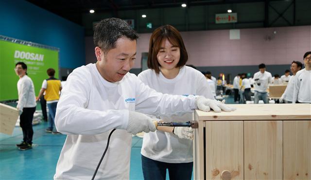 박정원 두산그룹 회장이 4월 19일 ‘두산인 봉사의 날’을 맞아 서울무역전시컨벤션센터에서 임직원들과 함께 지역사회 가정에 전달할 가구를 만들고 있다.
