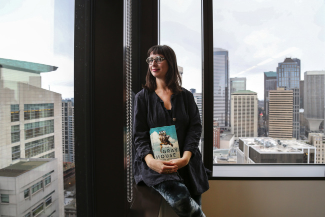 Gabriella Page-Fort, the editorial director for AmazonCrossing, poses for a portrait on March 8, in Seattle, while holding a copy of the book “The Gray House,” by Mariam Petrosyan. (Seattle Times/TNS)