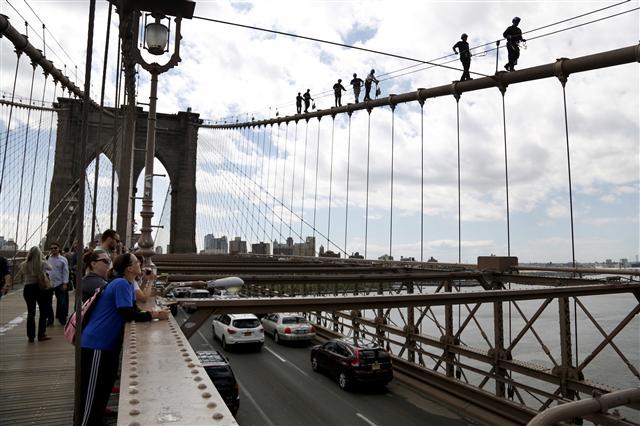 <YONHAP PHOTO-2615> In this Tuesday, May 2, 2017 photo, pedestrians watch as New York City police officers, including members of the Emergency Services Unit, walk down a cable on the Brooklyn Bridge during a training exercise in New York. The 400-team unit, an elite group of officers trained to handle the city???s most dangerous rescues, trains for months not only on technical rescue techniques, but also on how to talk to people to get them down safely. (AP Photo/Seth Wenig)/2017-05-09 13:57:55/ <저작권자 ⓒ 1980-2017 ㈜연합뉴스. 무단 전재 재배포 금지.>