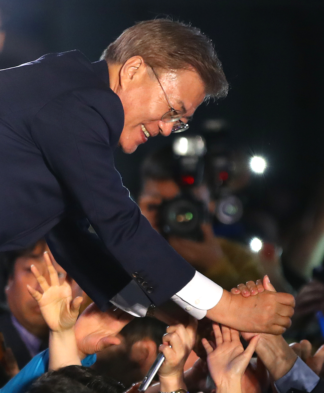 President Moon Jae-in shakes hands with supporters on Wednesday in Seoul. (Yonhap)