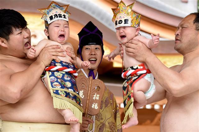 <YONHAP PHOTO-0354> TOPSHOT - Sumo wresters hold up crying babies in front of a referee (C) clad in a traditional costume during a "Baby-cry Sumo" event at the Kamegaike-Hachiman Shrine in Sagamihara, Kanagawa prefecture, on May 14, 2017. Some 150 babies aged under two took part in the annual baby crying contest in the Shinto shrine in Sagamihara. Japanese parents believe that sumo wrestlers can help make babies cry out a wish to grow up with good health. / AFP PHOTO / Toru YAMANAKA/2017-05-15 02:51:12/ <저작권자 ⓒ 1980-2017 ㈜연합뉴스. 무단 전재 재배포 금지.>