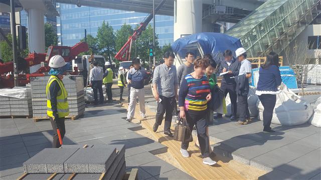 지하철 1호선 서울역 7ㆍ8번 출구 사이 교통섬의 서울로 7017 공사현장에서 일부 작업자들이 안전모를 쓰지 않고 일하고 있으며 그사이를 시민들이 위태롭게 지나가고 있는 모습(왼쪽 사진)과  서울역 서부교차로 일대 서울로 7017 공사현장에 공사용 흙이 널려있는 모습.
