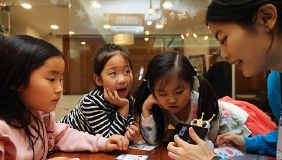 In this file photo taken on Dec. 14, 2017, a member of the nonprofit foundation Like Lion teaches kids basic coding at a kids cafe in Seoul. (Yonhap)