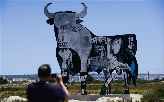 <YONHAP PHOTO-0260> A man takes pictures of the famous silhouette of the Spanish roads, the Osborne black bull painted with Spanish artist Pablo Picaso's masterpiece "Guernica" in Santa Pola, southeastern Spain on May 24, 2017. Northern Spanish town of Guernica mark this year the 80th anniversary of its bombing by Nazi warplanes during the Spanish civil war which inspired Pablo Picasso's famed "Guernica" painting. / AFP PHOTO / JOSE JORDAN / RESTRICTED TO EDITORIAL USE - MANDATORY MENTION OF THE ARTIST UPON PUBLICATION - TO ILLUSTRATE THE EVENT AS SPECIFIED IN THE CAPTION/2017-05-25 00:57:48/ <저작권자 ⓒ 1980-2017 ㈜연합뉴스. 무단 전재 재배포 금지.>