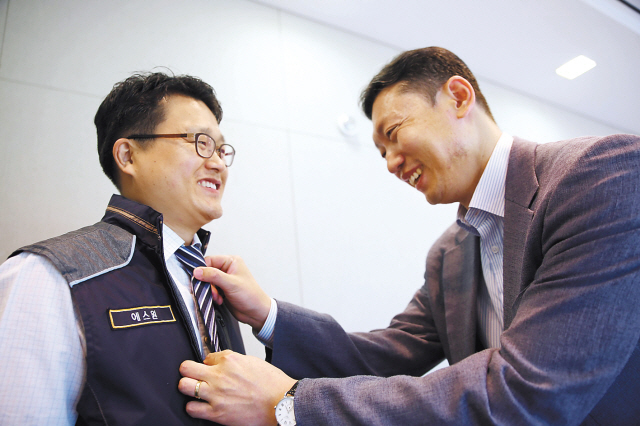 에스원이 최근 진행한 ‘원 패밀리 행사’에서 문남수 BE 사업부 상무가 김용 병원FM그룹 소장에게 자신의 넥타이를 매주고 있다.