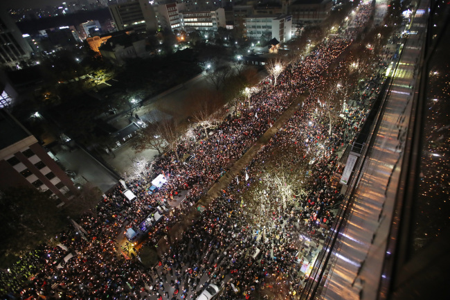 Protesters hold candles at a rally held near the Constitutional Court in central Seoul. (Yonhap)