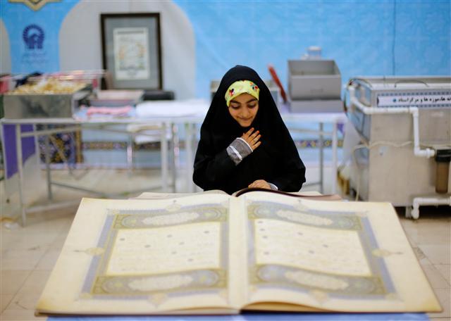 <YONHAP PHOTO-1359> epa06004202 An Iranian girl stands in front of a huge copy of the holy book of Koran at the Koran exhibition during the holy month of Ramadan, in Tehran, Iran, 01 June 2017. The exhibition runs until 14 June. The exhibition runs until 14 June. Muslims around the world celebrate the holy month of Ramadan by praying during the night time and abstaining from eating, drinking, and sexual acts during the period between sunrise and sunset. Ramadan is the ninth month in the Islamic calendar and it is believed that the revelation of the first verse in Koran was during its last 10 nights./2017-06-02 05:55:49/ <저작권자 ⓒ 1980-2017 ㈜연합뉴스. 무단 전재 재배포 금지.>