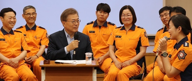 President Moon Jae-in listens as a female firefighter speaks during a visit to Yonsan Fire Station in central Seoul on Wednesday. (Yonhap)