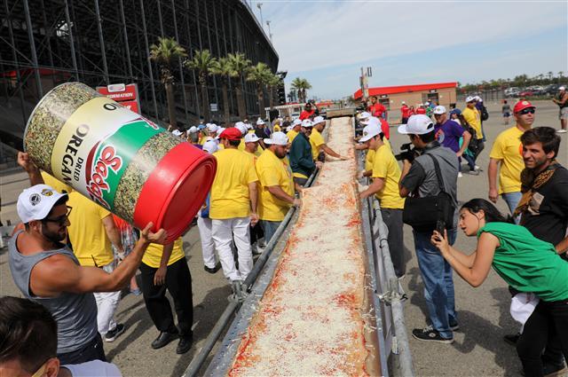 <YONHAP PHOTO-2859> epa06022010 Volunteers finish placing toppings onto their Guinness World Record attempt for the Longest Pizza in Fontana, California, USA, 10 June 2017. The pizza was planned to be 7000 feet (2.13 km) to break the previous record of 6082 feet (1.8 km) set in Naples, Italy in 2016. EPA/EUGENE GARCIA/2017-06-11 13:01:07/ <저작권자 ⓒ 1980-2017 ㈜연합뉴스. 무단 전재 재배포 금지.>