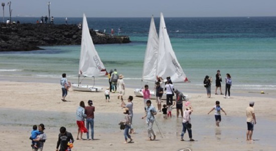 Tourists walk on a beach on the southern resort island of Jeju on May 7, 2017, the final day of a "golden holiday week" in South Korea. (Yonhap)
