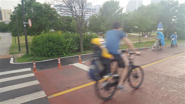 서울 중구 남산공원 정상 주변 도로에 있는 자전거 ‘20㎞/h 속도제한’ 표지판(왼쪽 사진) 서울 영등포구 여의도 한강공원에서 한 자전거 운전자가 속도를 내고 있다.