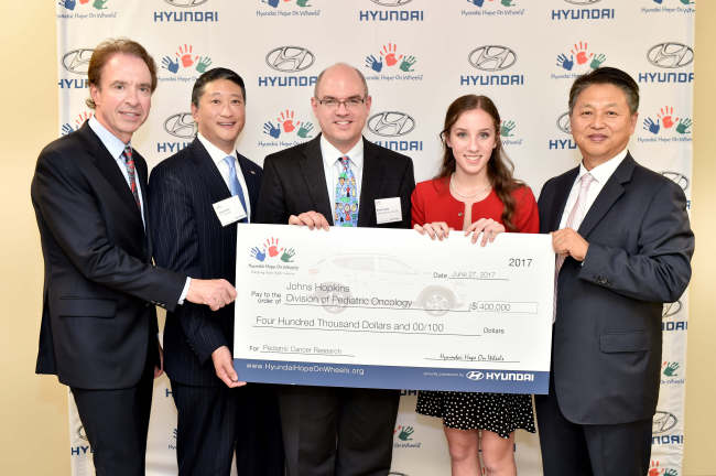 Jerry Flannery, executive vice president of Hyundai Motor USA (left) poses with the recipient of the Hyundai Hope on Wheels research grant Brian Ladle (center), a pediatric oncologist at Johns Hopkins Children’s Center, at an event held in Washington, Tuesday. (Hyundai Motor)　