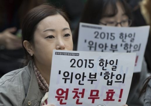 In this file photo, a protester holds a sign opposing a 2015 Seoul-Tokyo deal to settle the issue of former Korean sex slaves for Japanese troops during World War II at a rally in front of the Japanese Embassy in Seoul on March 22, 2017. (Yonhap)