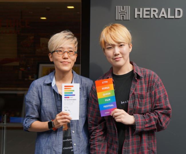 From left to right: Holic and Ha-re stand outside the Korea Herald building with this year’s film festival programs. (Paige Shin/The Korea Herald)