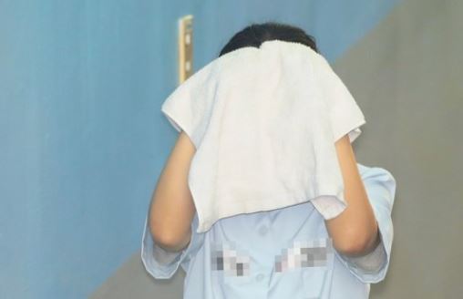 Choi You-jeong, a judge-turned-lawyer convicted of bribery charges in a high-profile lobbying scandal, walks her way into the courthouse covering her face with a towel for an appeals trial in Seoul on July 21, 2017. (Yonhap)