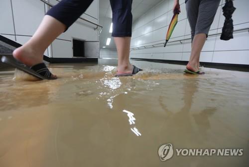 (사진=연합뉴스)서울을 비롯한 수도권 곳곳에 호우경보가 내려진 23일 오전 인천 남구 주안역의 지하출입통로에 물이 차 시민들이 불편을 겪고 있다.