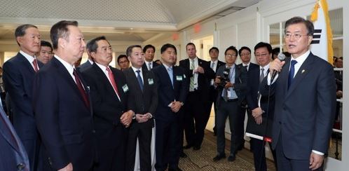 President Moon (Right) speaks to a group of business people accompanying him on a trip to the U.S. in late June during a tea meeting. (Yonhap)