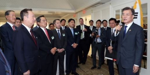 In this file photo taken on June 29, 2017, President Moon Jae-in (R) speaks to a group of business people accompanying him on a trip to the U.S. during a tea meeting. (Yonhap)
