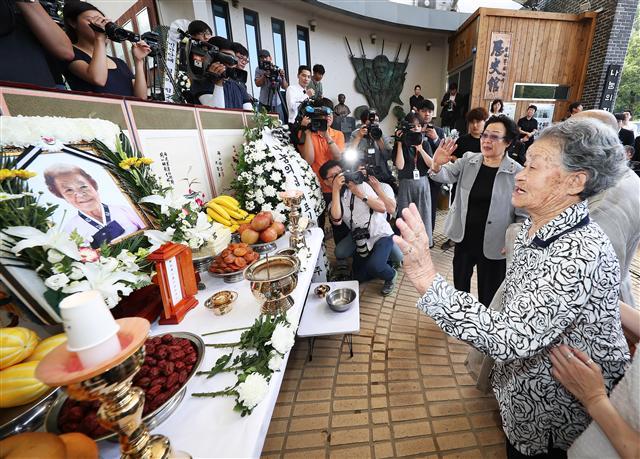 25일 오전 경기도 광주시 퇴촌면 나눔의집에서 열린 일본군 위안부 피해자 김군자 할머니 노제에서 이용수 할머니와 박옥선 할머니가 헌화를 마치고 영정을 향해 손을 흔들며 인사를 하고 있다. 김 할머니의 별세로 정부에 등록된 일본군 위안부 피해자 239명 가운데 생존자는 37명으로 줄었다.  [연합뉴스]